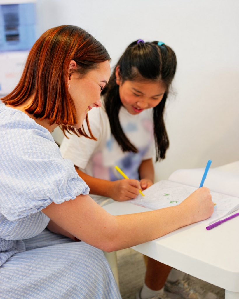 A young person and a team member drawing together at a table